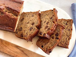 A loaf of rum raisin banana bread with four slices cut off and laying next to each other.