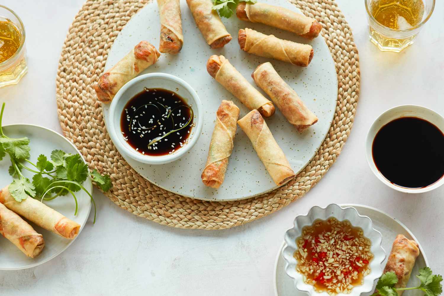 Overhead view of a platter of fried spring rolls with a dipping sauce on the platter and another dipping sauce next to it.