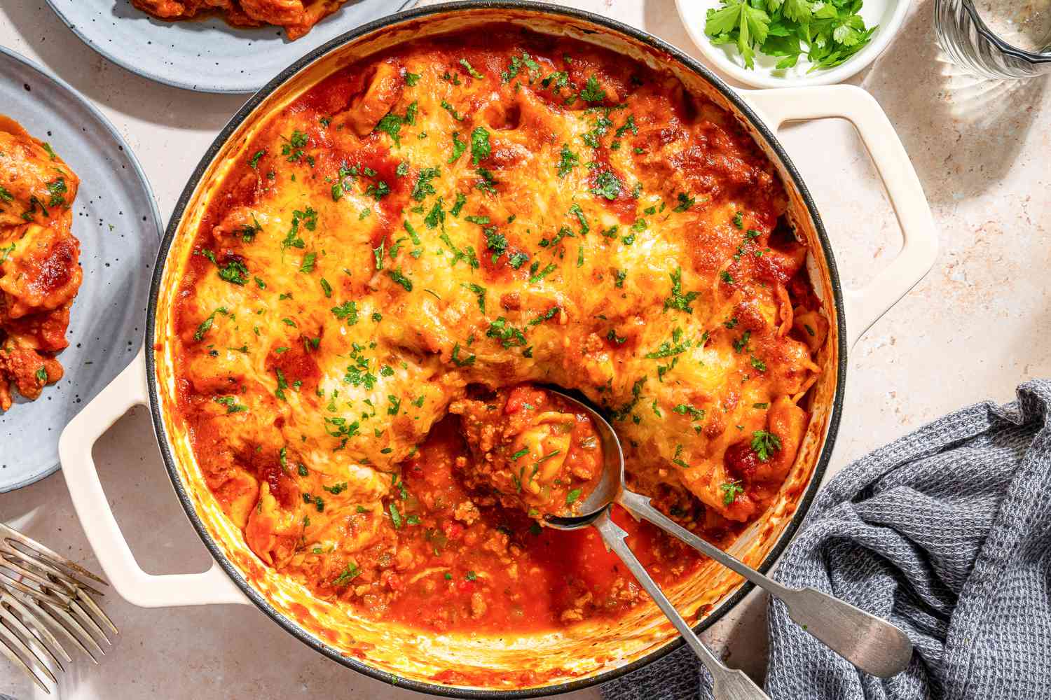 overhead view of Tortellini Pasta Bake in a baking dish, large spoons scooped out a serving