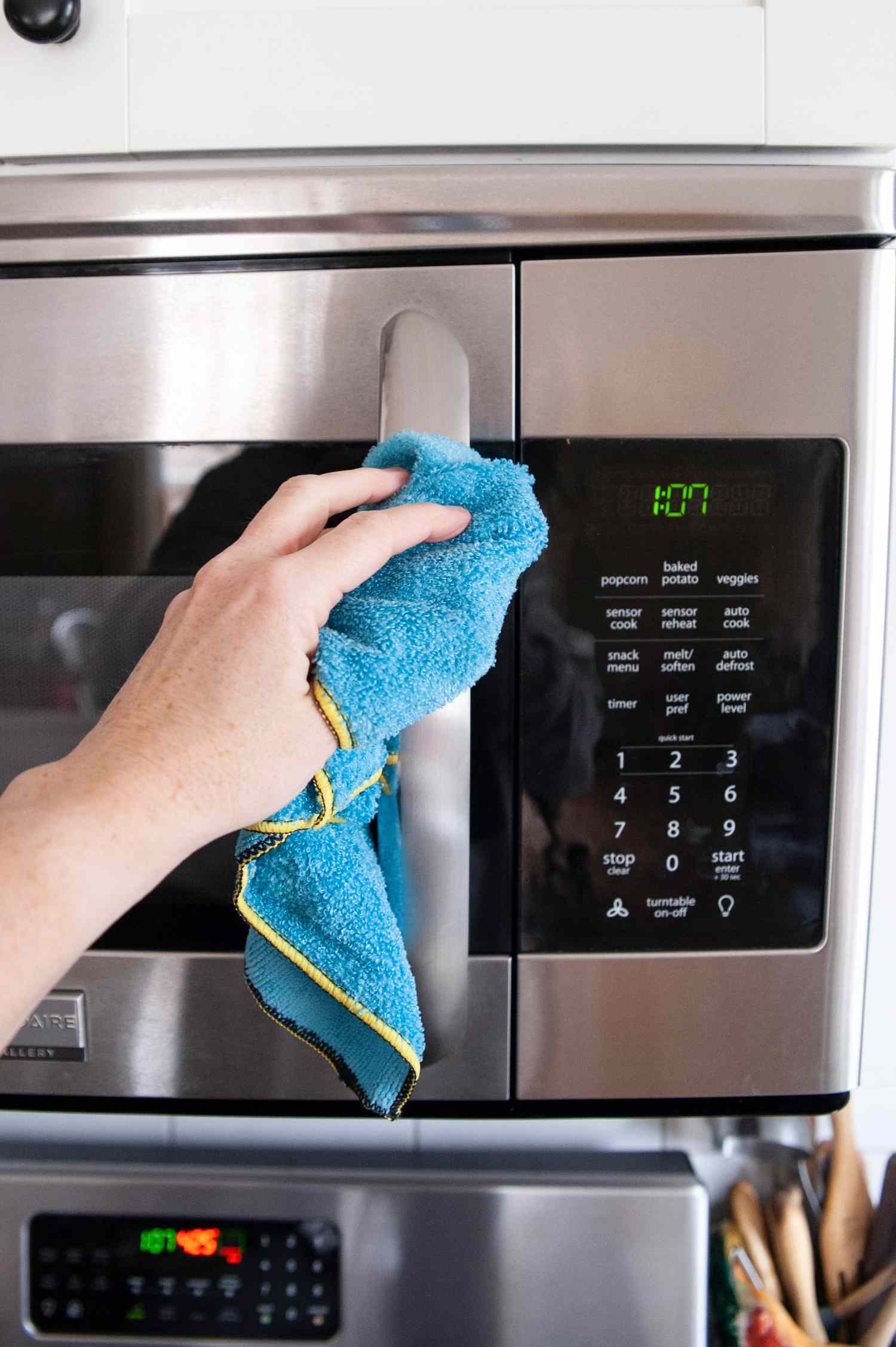 Hand Wiping the Exterior of a Mounted Microwave 