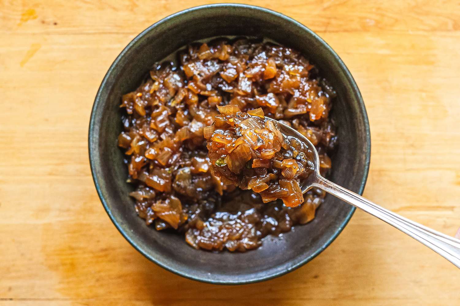 Balsamic onion jam in a grey bowl with a spoon.