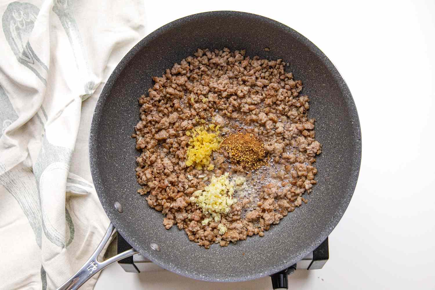 Aromatics Added to Ground Pork in a Pan on a Portable Burner Next to a White Kitchen Towel for Sichuan Mapo Tofu Recipe
