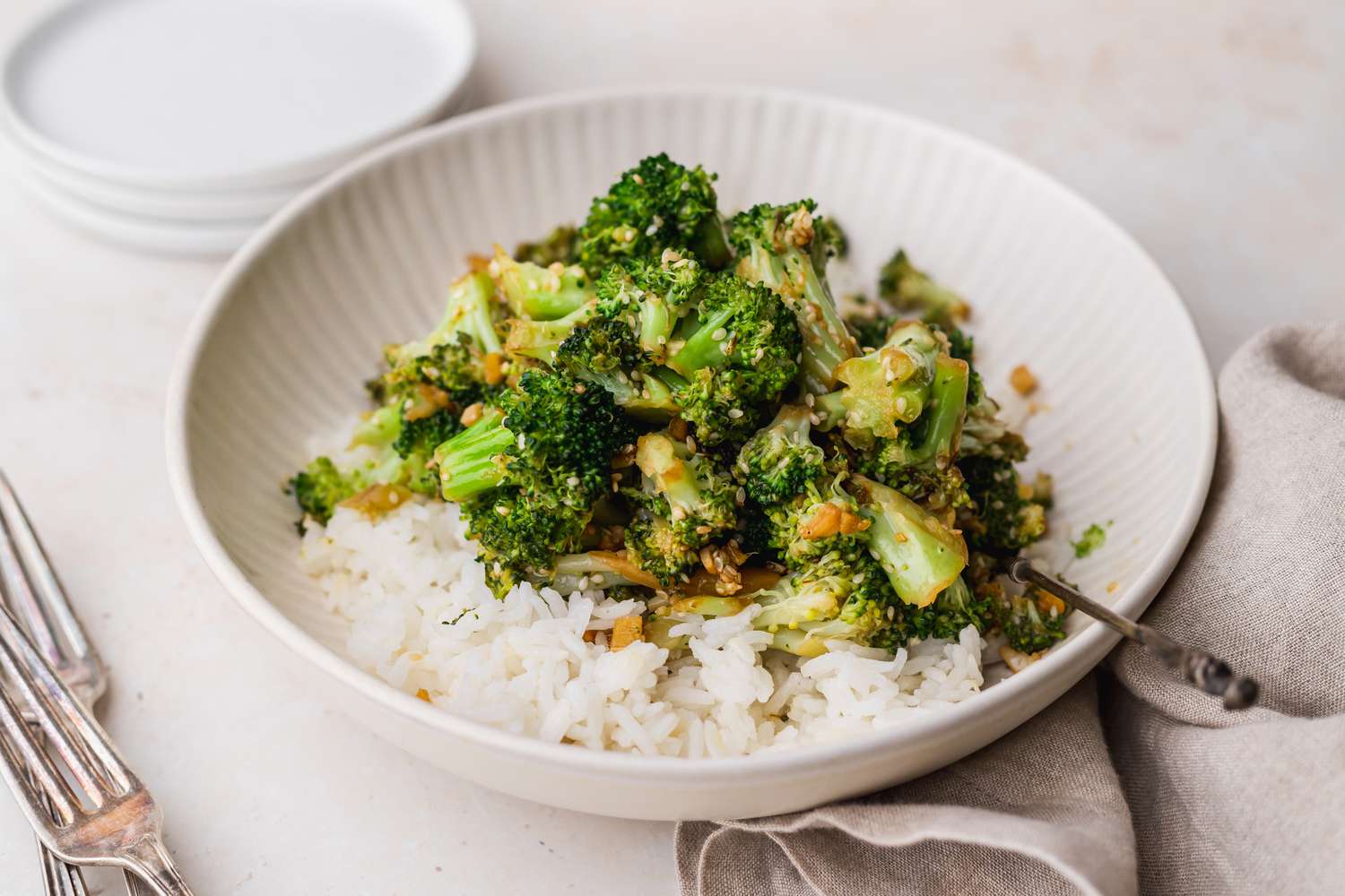 Side view of a bowl of stir fry broccoli served over rice.