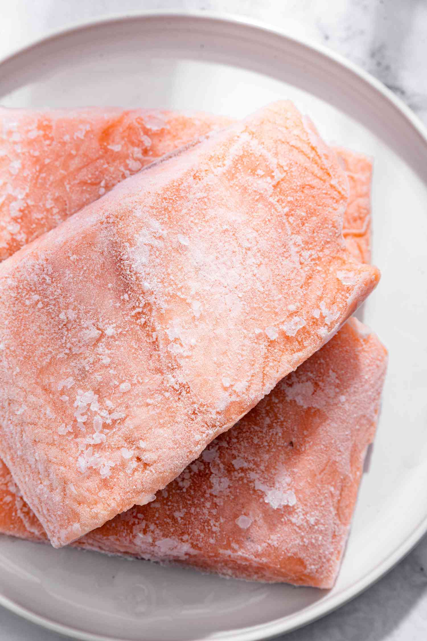 Three frozen salmon fillets on a plate