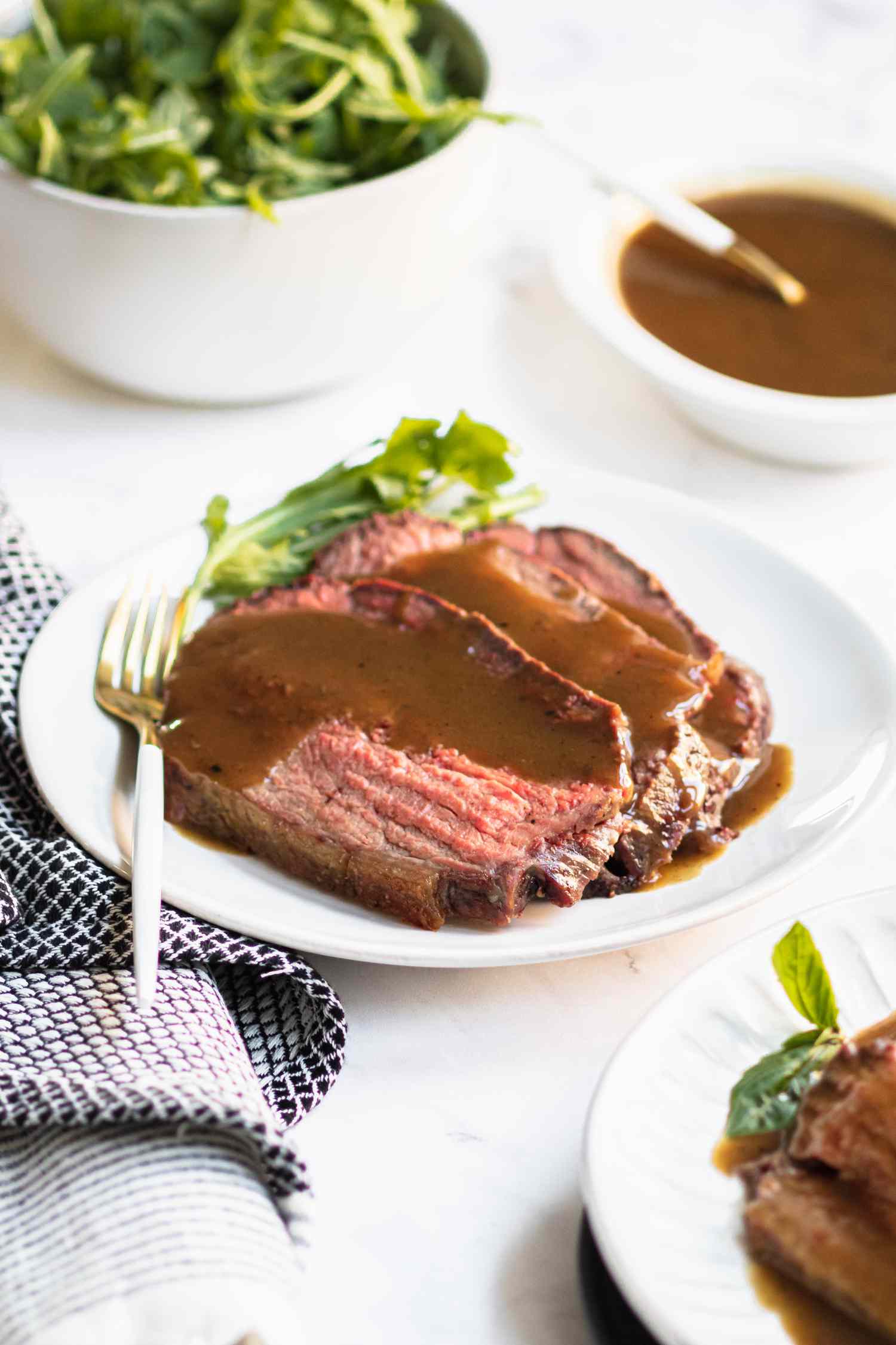 A plate of rump roast sliced and topped with gravy.