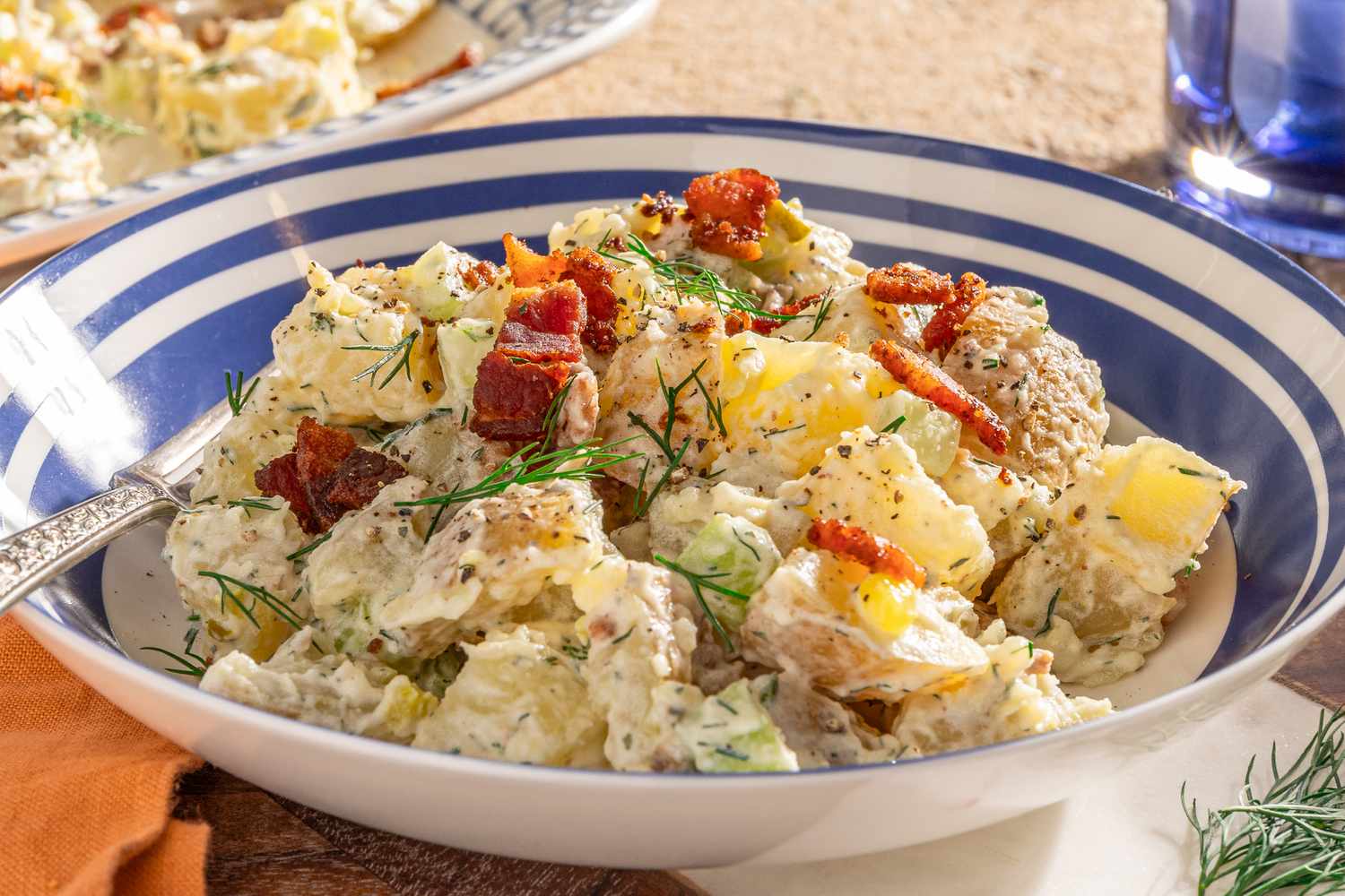 bowl of ranch potato salad, and in the background, a platter wtih more and a glass of water