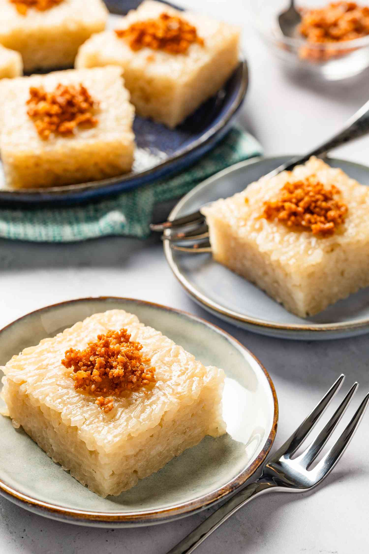 slices of slice of biko (Filipino sticky rice cake) on small plates and more on a larger plate