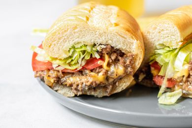 Two Halves of a Chopped Cheese Sandwich on a Plate 