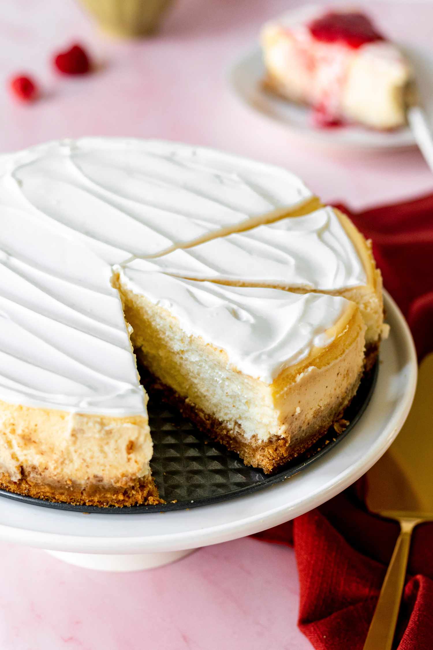 A cheesecake on a cake stand with a couple slices cut.