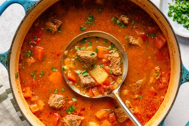 Overhead view of a dutch oven of Hungarian goulash with a ladle in the center with a serving inside
