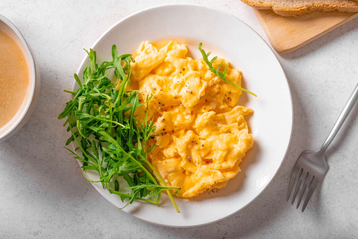 overhead view of a plate of scrambled eggs and a side of greens