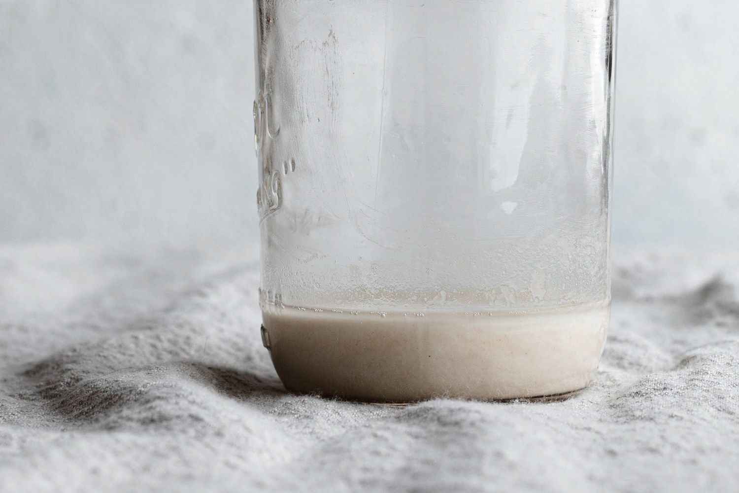Close up of a mason jar on a linen for a sourdough starter recipe