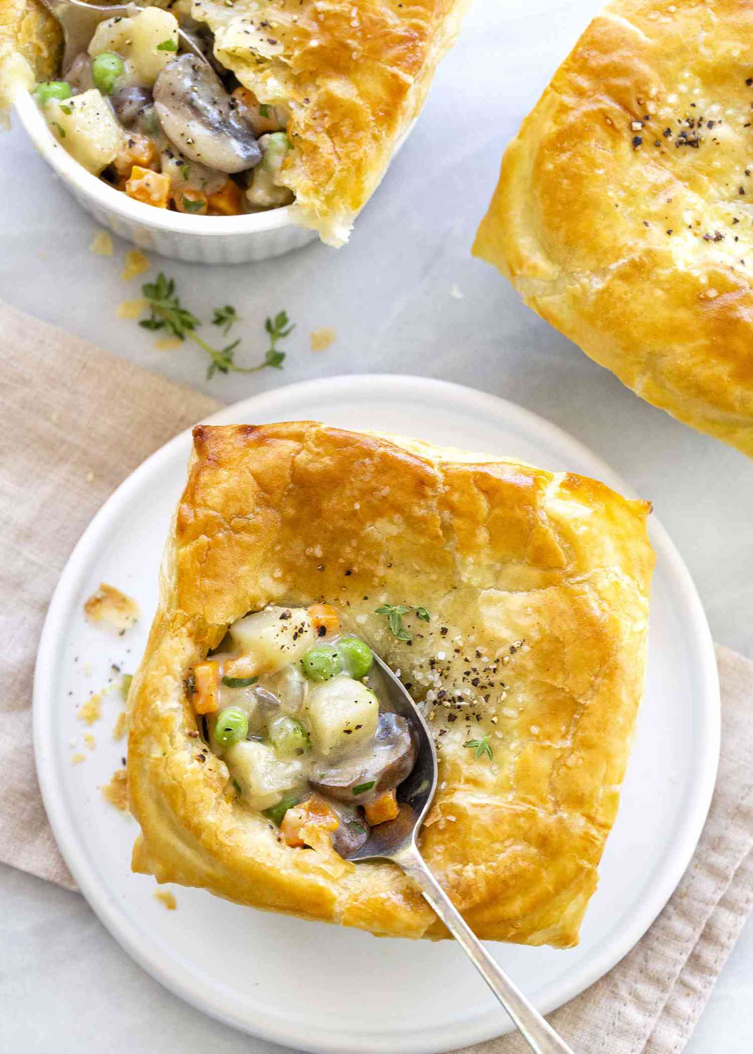 Homemade vegetable pot pie on white plate with spoonful take out.