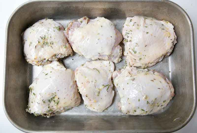 Six pieces of butter brushed lemon chicken in a baking dish