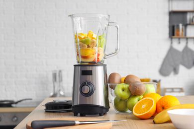 A blender with fresh fruit on a kitchen table