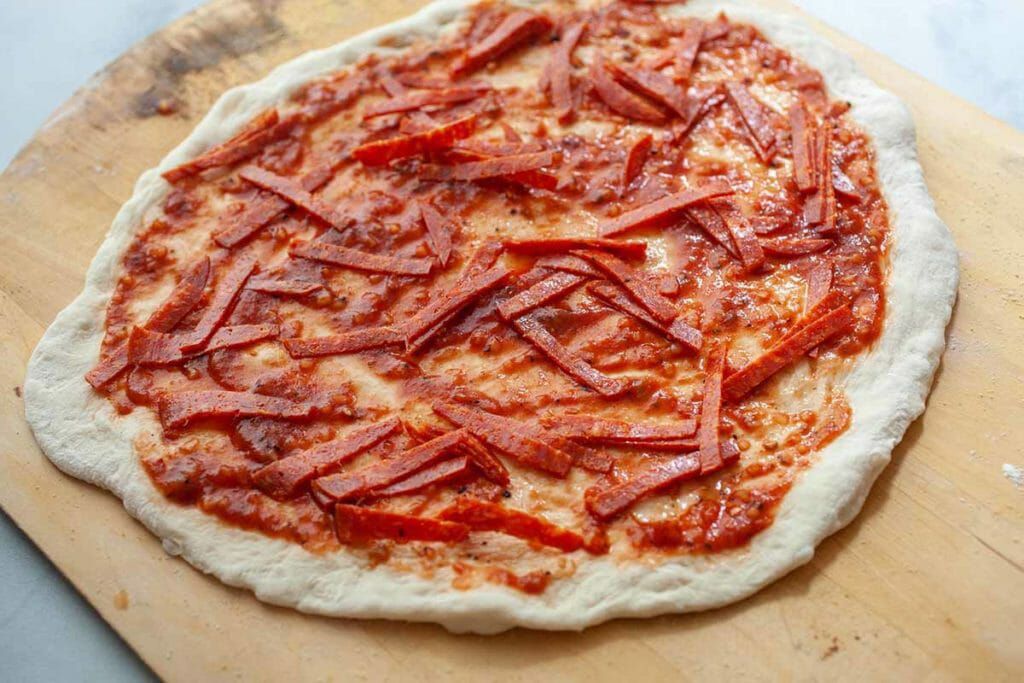 Put slices of pepperoni under the cheese layer on your homemade pepperoni pizza
