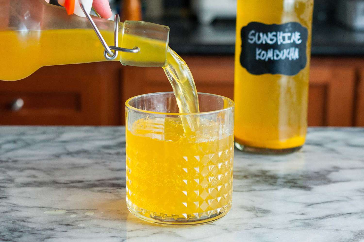 Pouring homemade kombucha into a glass