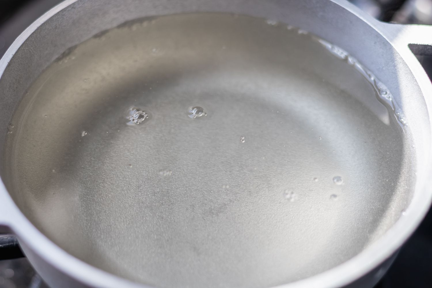 Sugar diluting in a pot of water to make a pink lemonade recipe.