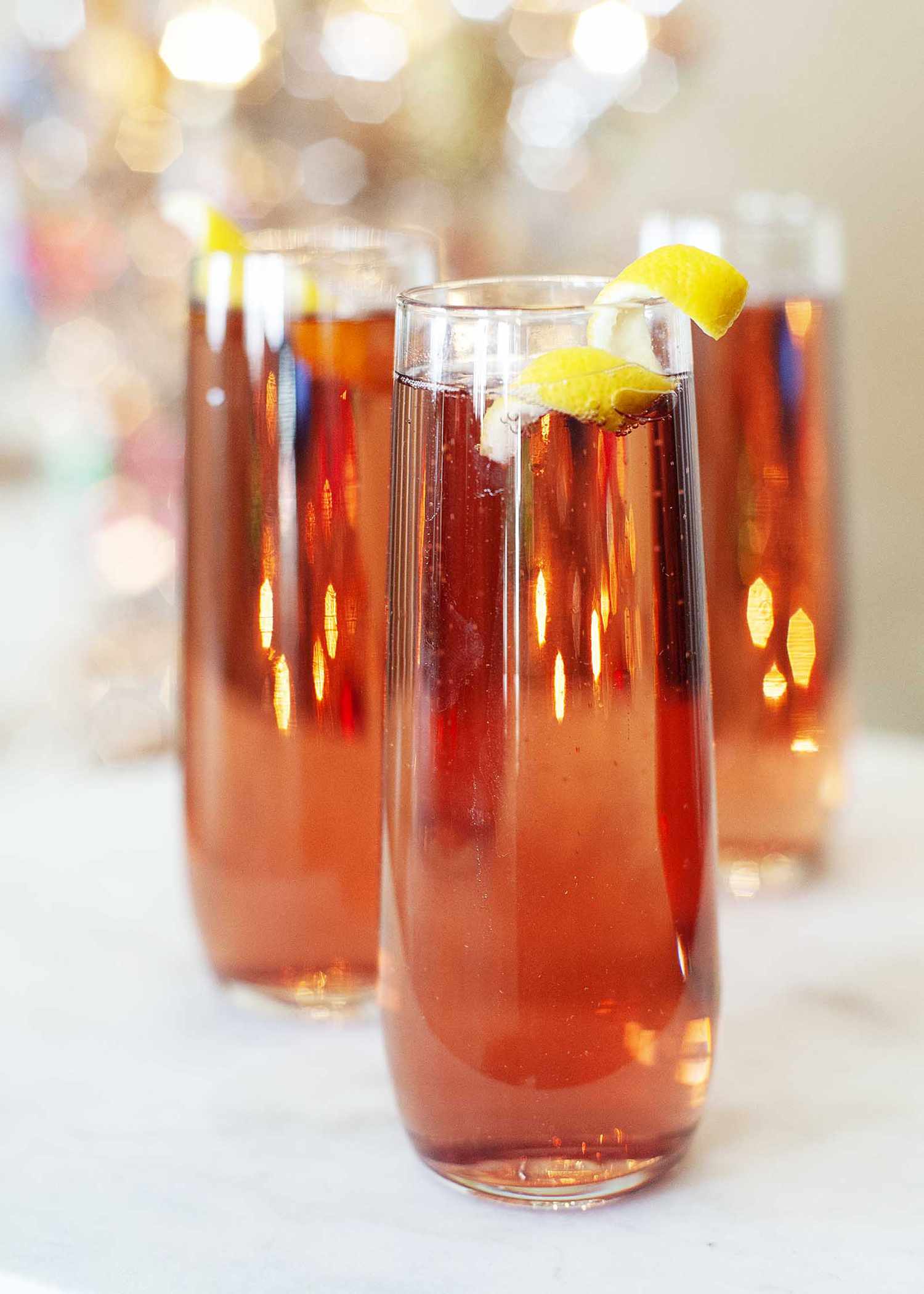 Side view of kir royale in three tall and slender glasses on a blurred sparkling background