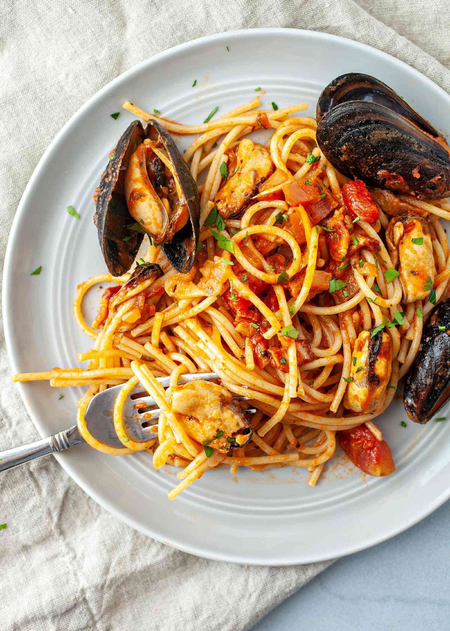 Mussels in Spicy tomato sauce recipe - overhead shot of spaghetti on plate with mussels on side