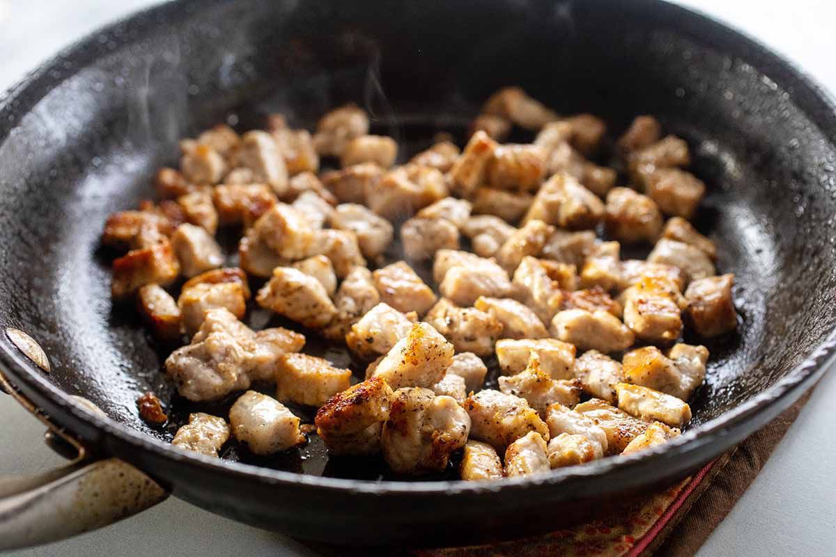 A black skillet has chopped sauteed pork inside it.