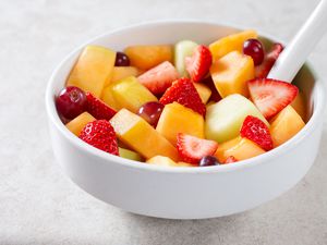 A bowl of fresh fruit salad containing melon, strawberries, grapes, and other fruit pieces