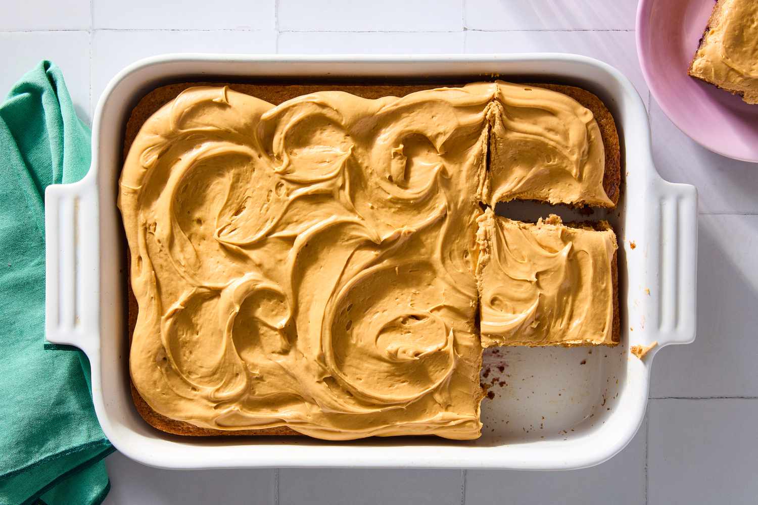 A white baking dish with the a baked white spiced cake, with swirled with dulce de leche frosting