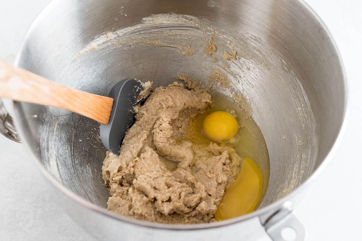 Adding eggs to the butter and sugar for homemade chocolate chip cookies.