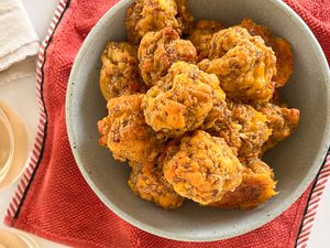 Overhead view of a green bowl of sausage balls resting on a red towel on a white countertop