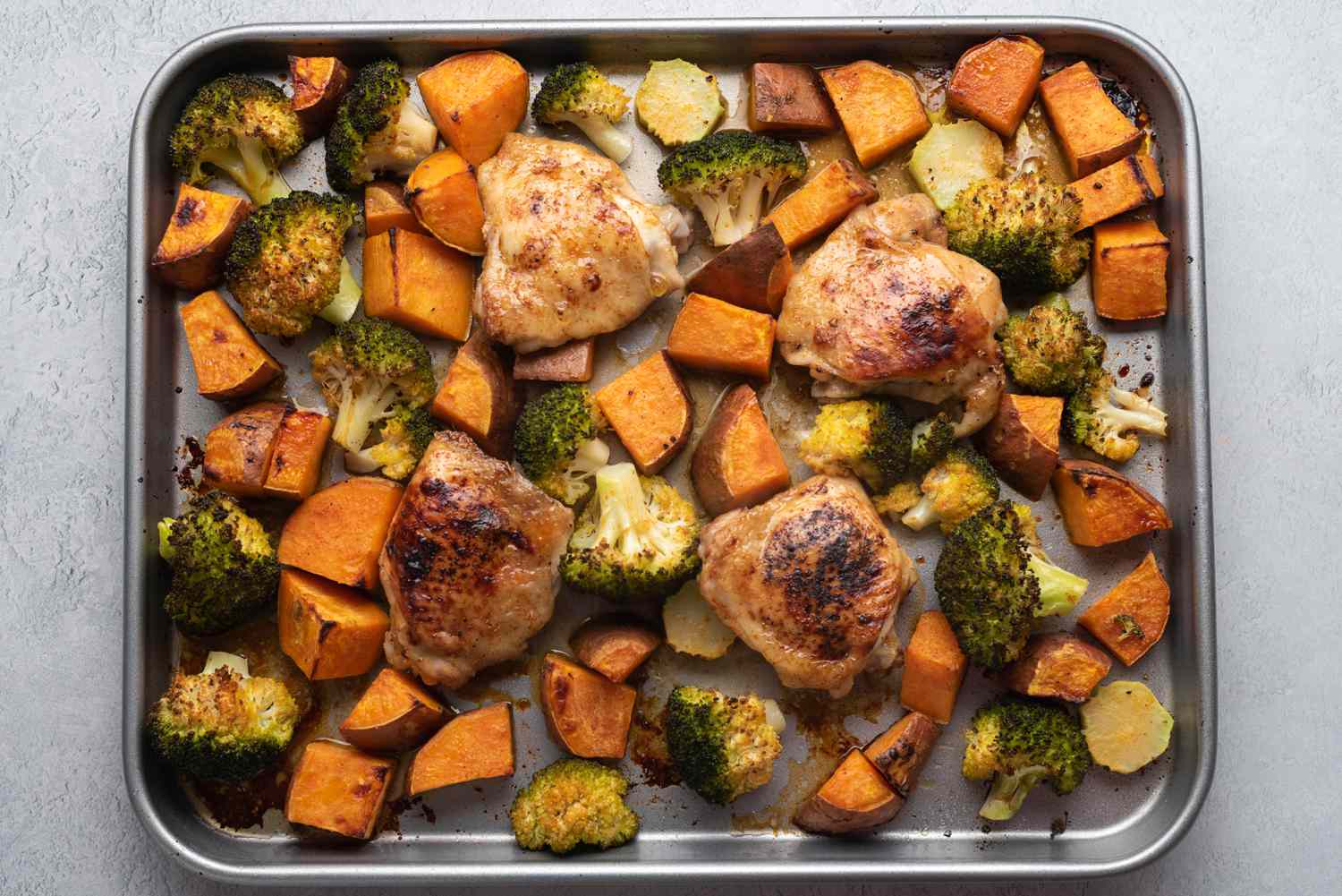 Roasted Sheet Pan Chicken, Sweet Potatoes, and Broccoli on a sheet pan 