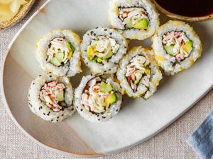 California Rolls on a Plate Next to a Small Bowl of Soy Sauce, Small Bowl of Pickled Ginger, and Small Saucer of Wasabi