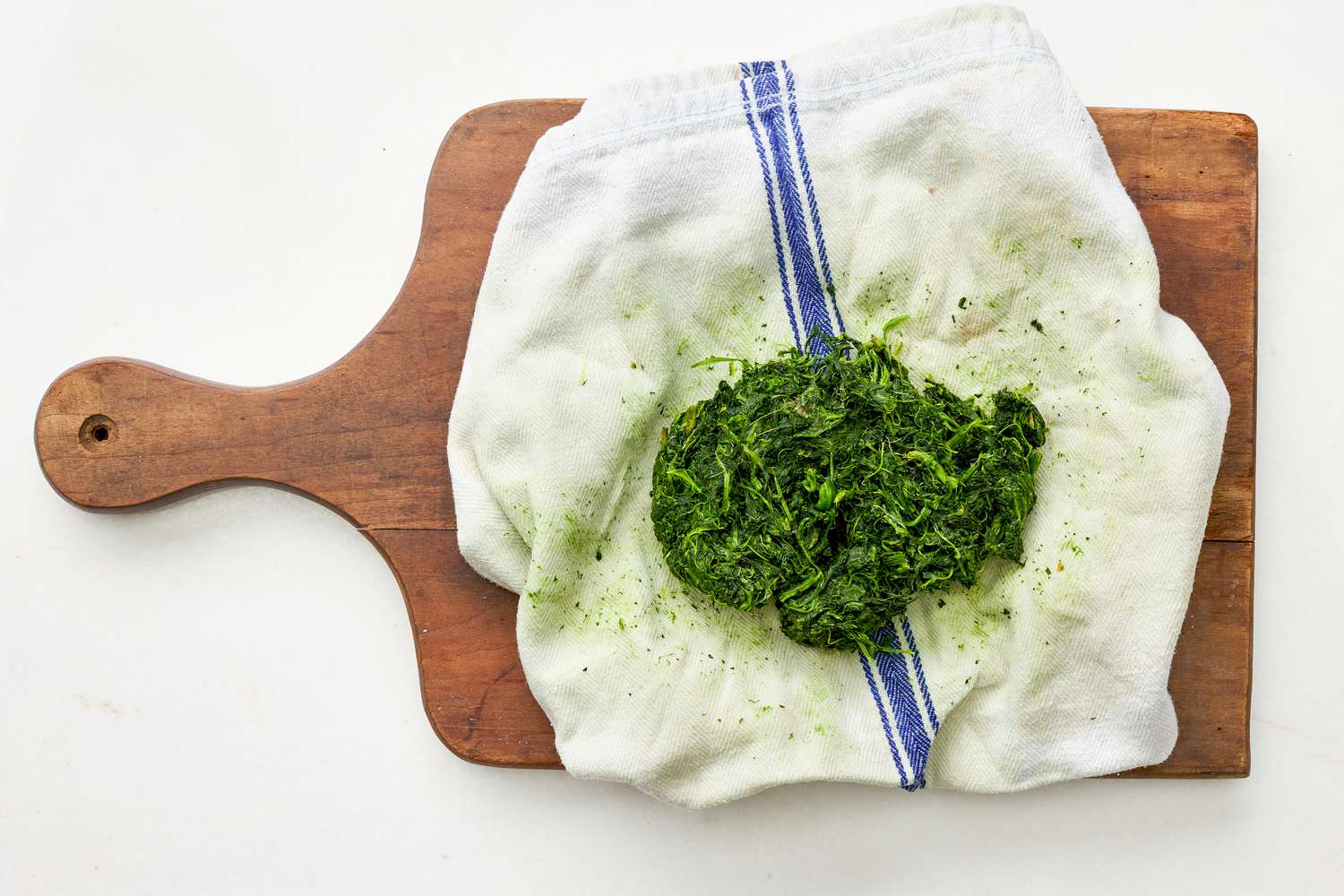 Frozen spinach in a kitchen towel after squeezed to remove all moisture for spinach flornetine breakfast casserole recipe