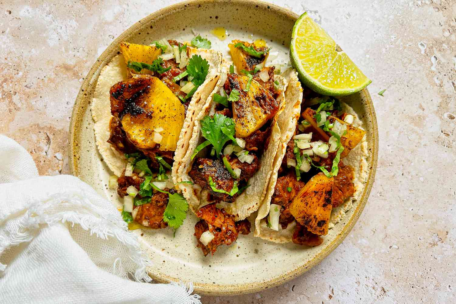 Plate of Tacos al Pastor with Pork, Pineapple, Cilantro, and a Lime Wedge 