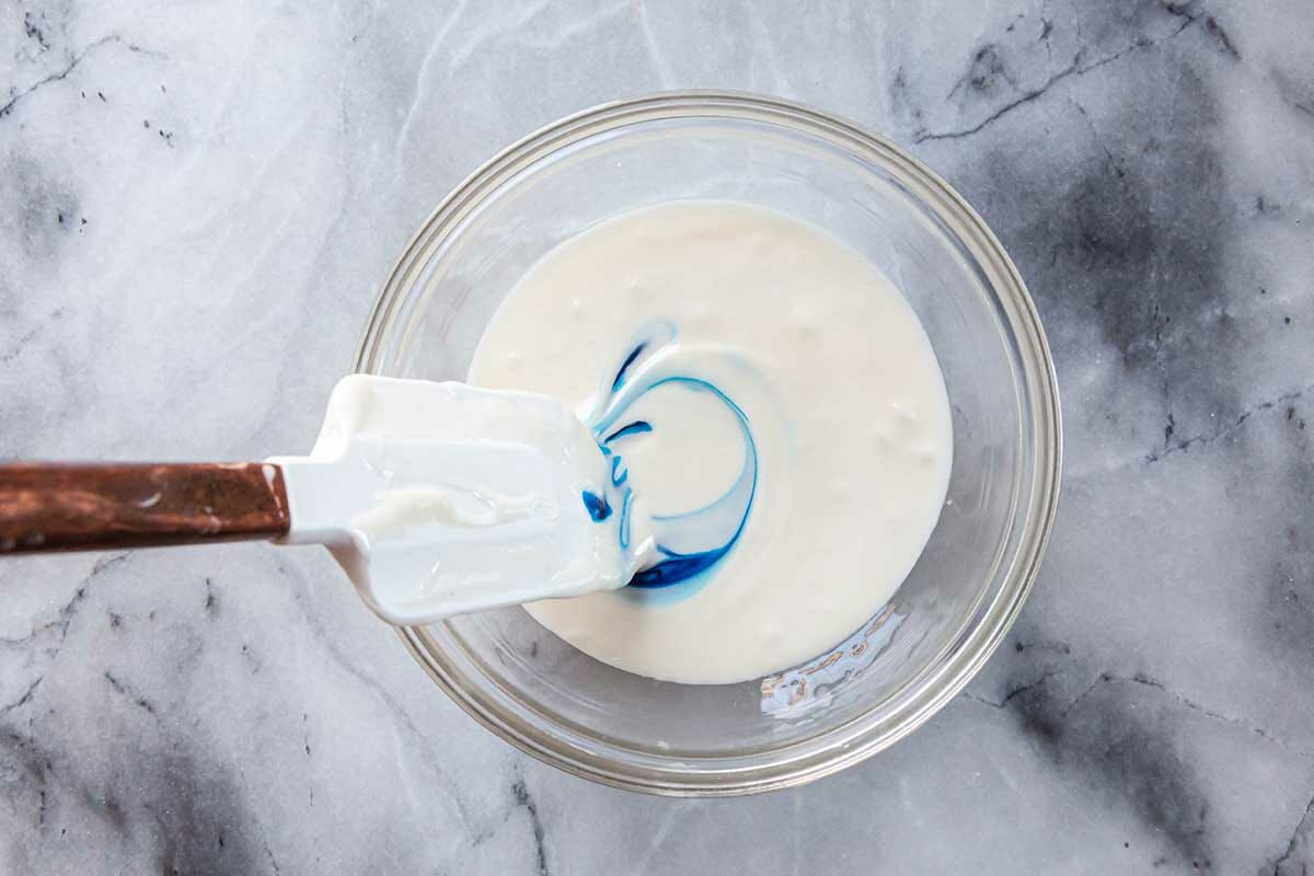 How to make royal icing by swirling blue food coloring in a bowl of white frosting.
