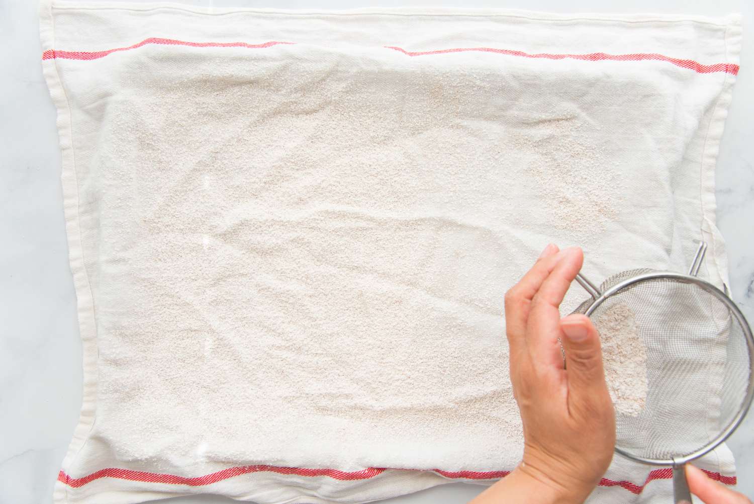 Dusting a tea towel with powdered sugar to make a Brazo Gitano (Spanish Roll Cake).