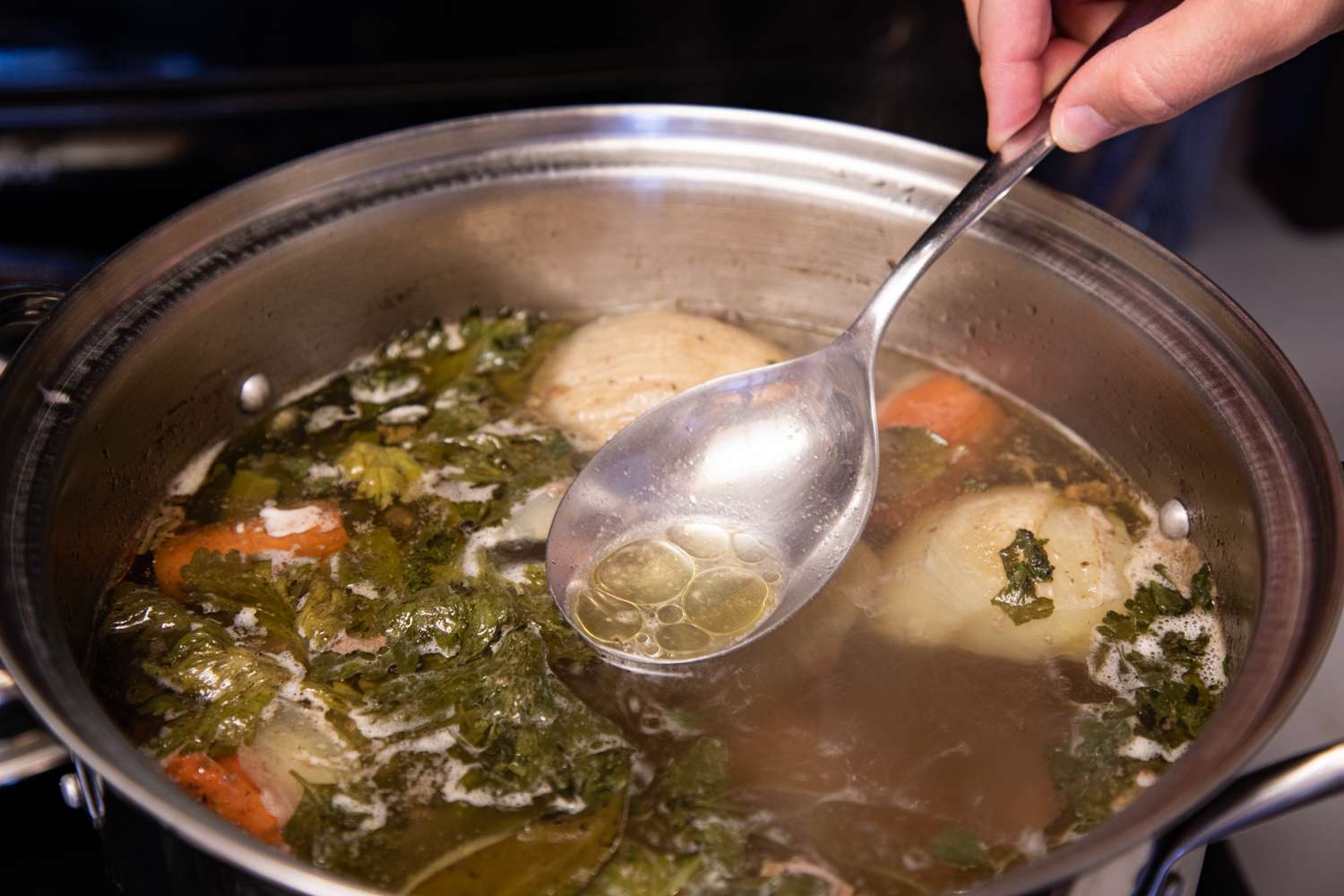 Skimming fat off the the pot for a bone broth recipe.