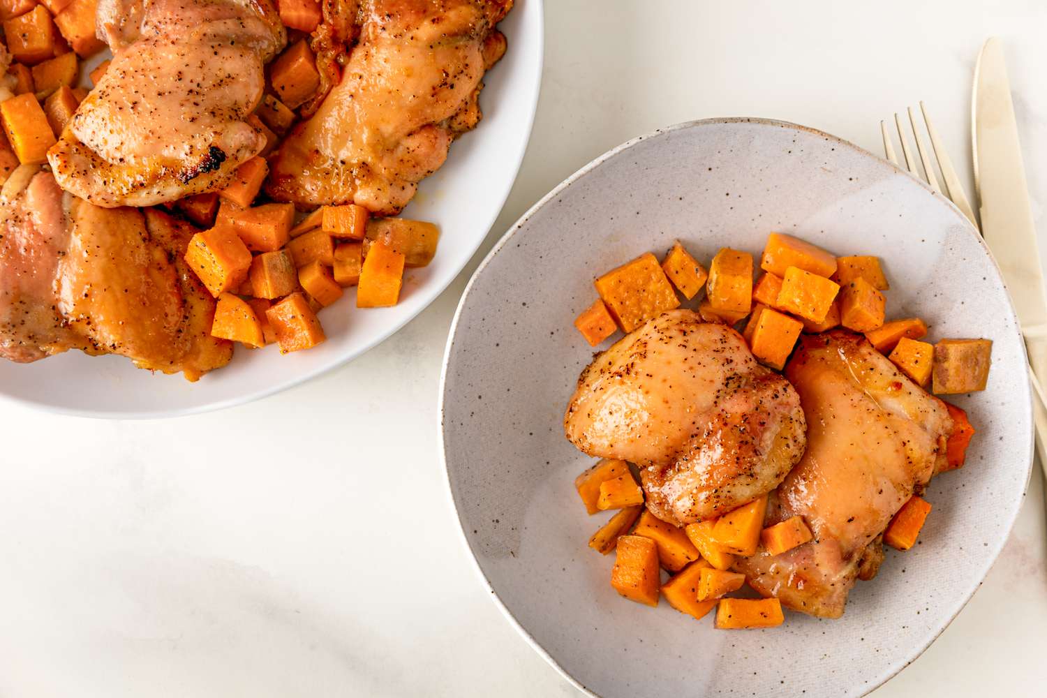 Overhead view of a white platter plus a bowl of roast chicken and sweet potatoes recipe 
