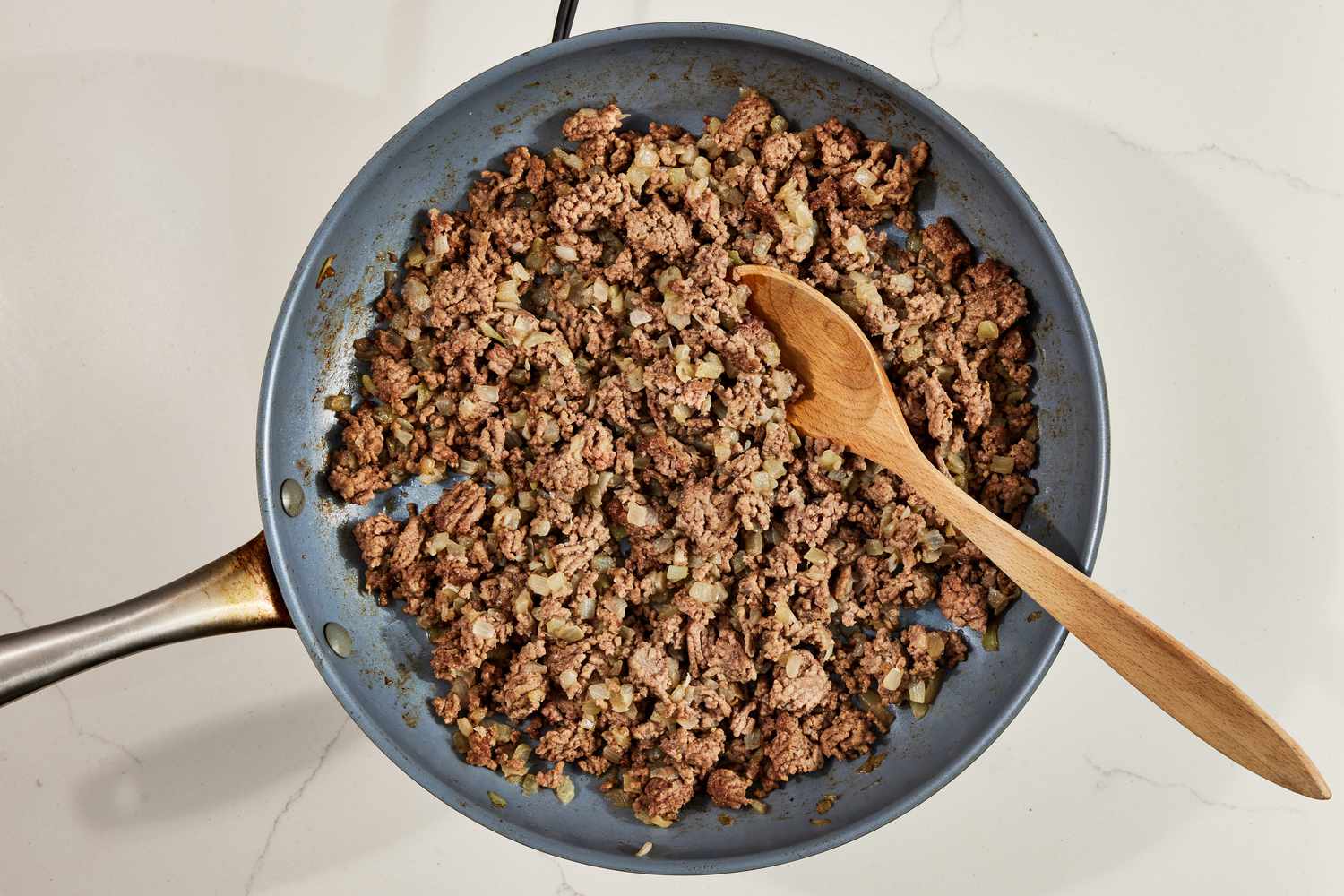Cooked beef topping in a pan with a wooden spoon for walking tacos recipe
