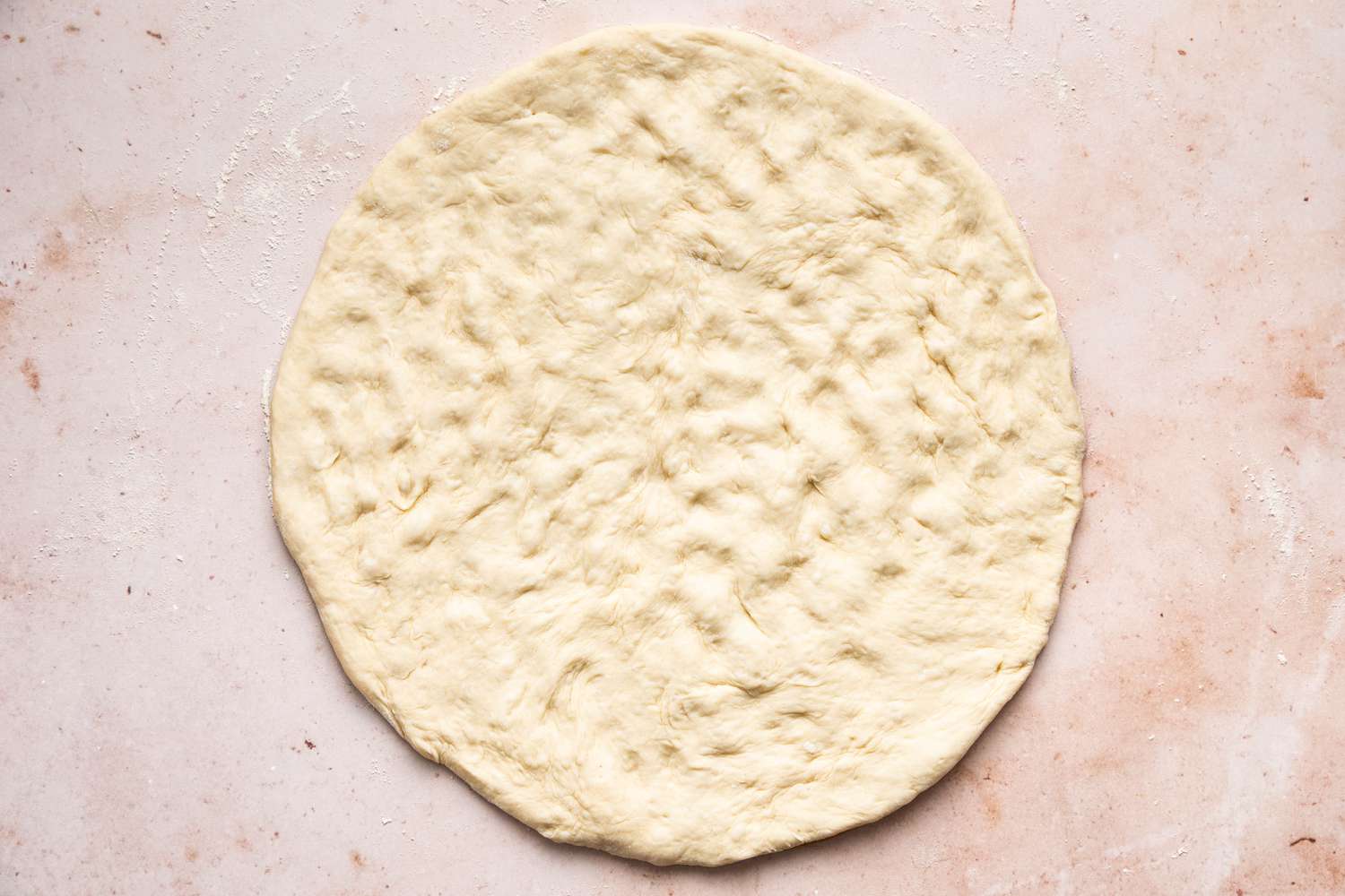 shaping a round of pizza dough for pickle pizza