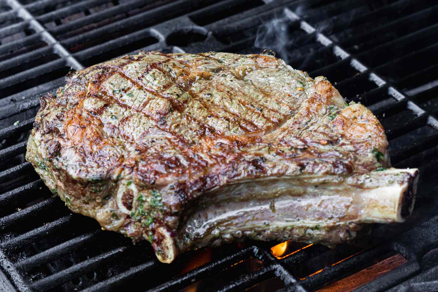 A cowboy steak cooking on the grill.