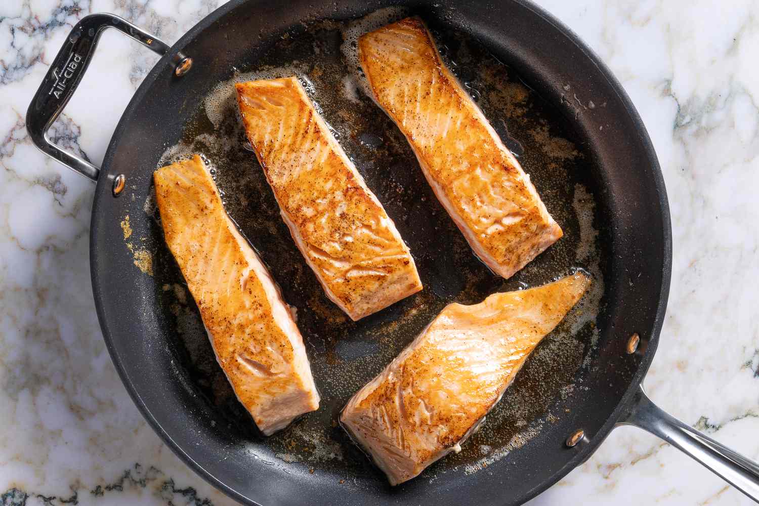 Salmon fillets getting pan fried skin side down