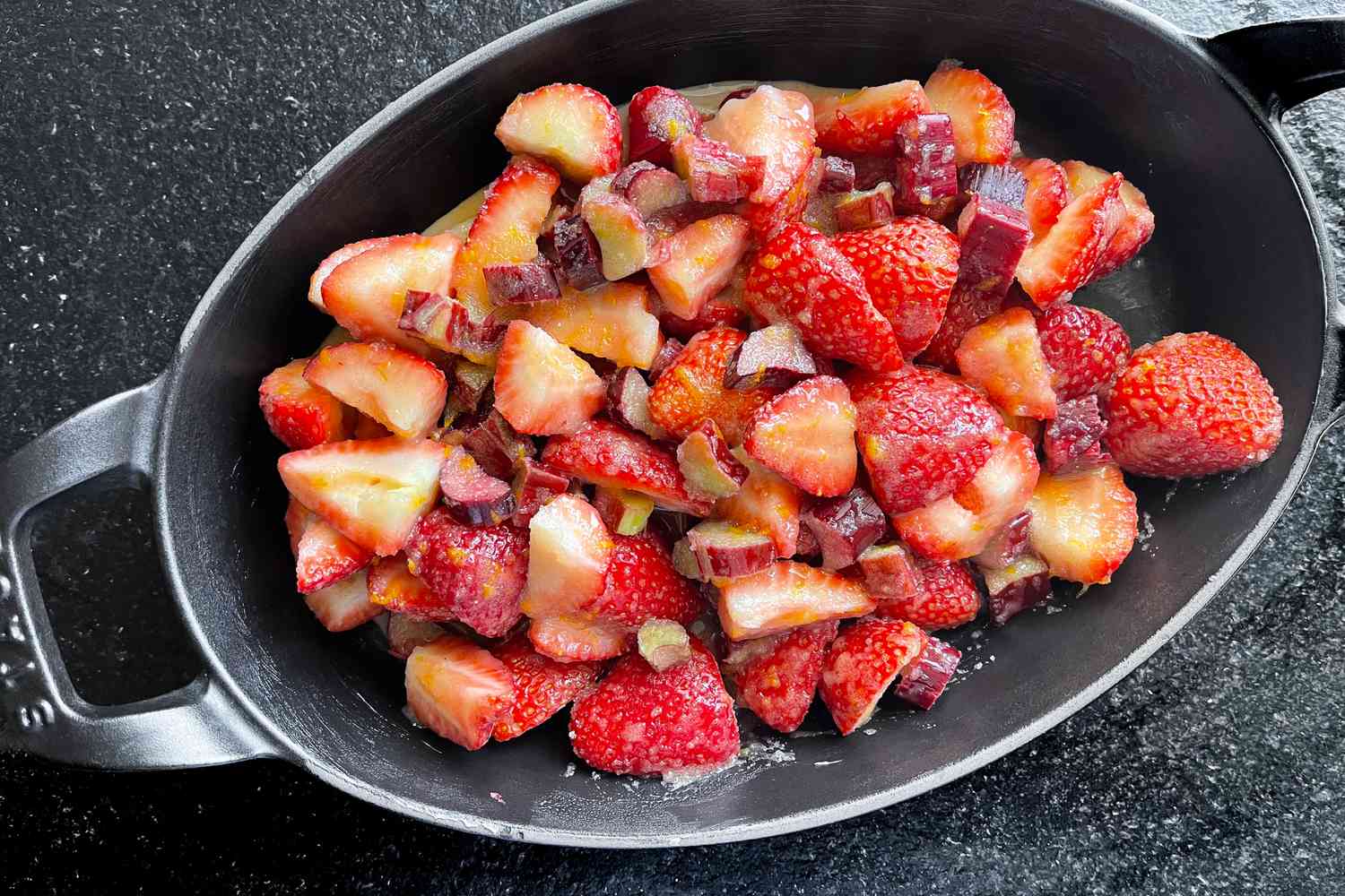 A black dish containing chopped strawberries and diced rhubarb
