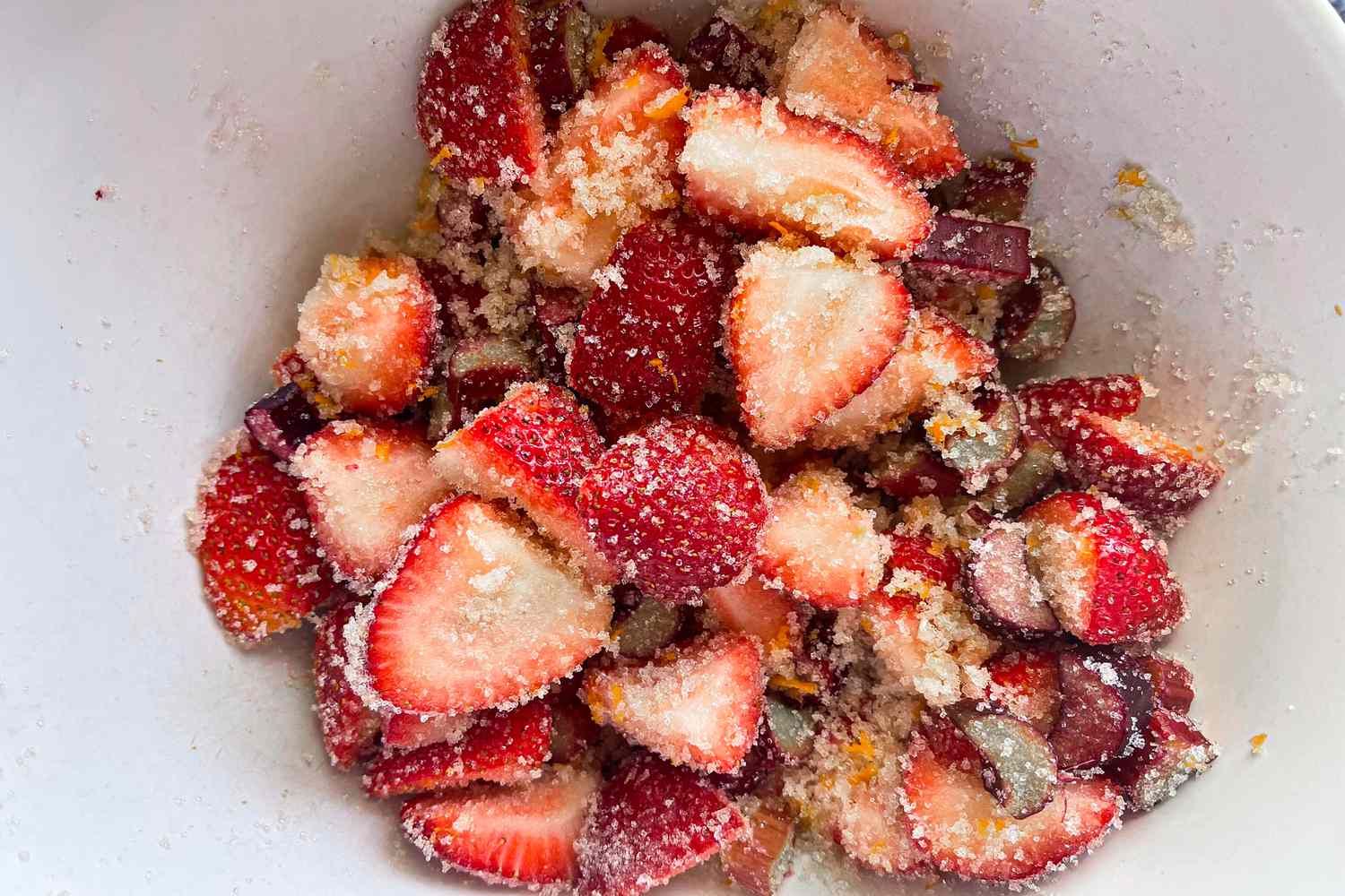 Sliced strawberries mixed with sugar in a bowl, preparation for a dessert topping or filling