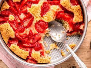 pan of strawberry spoon cake (missing a few bites) with a spoon resting in the pan