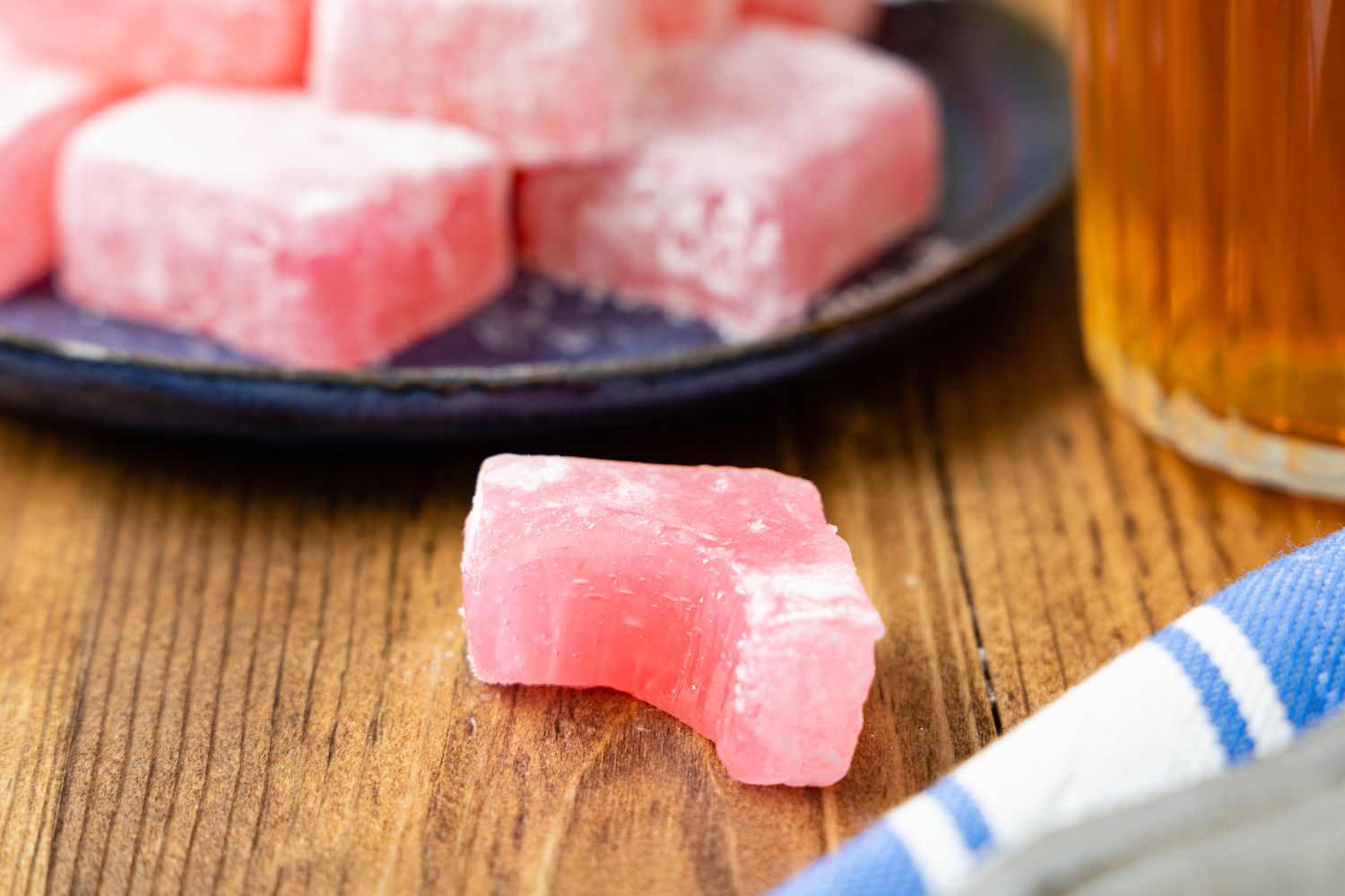 Piece of Bitten Turkish Delight on the Counter, and in the Surroundings, a Plate With More Turkish Delight, a Cup of Tea, and a Kitchen Towel