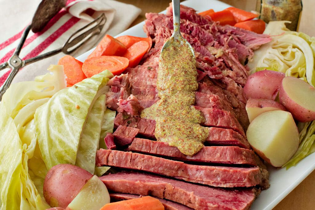 Crockpot Corned Beef - drizzling mustard on sliced corned beef