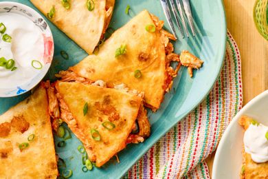 Quesadillas on a plate with a small bowl of sour cream