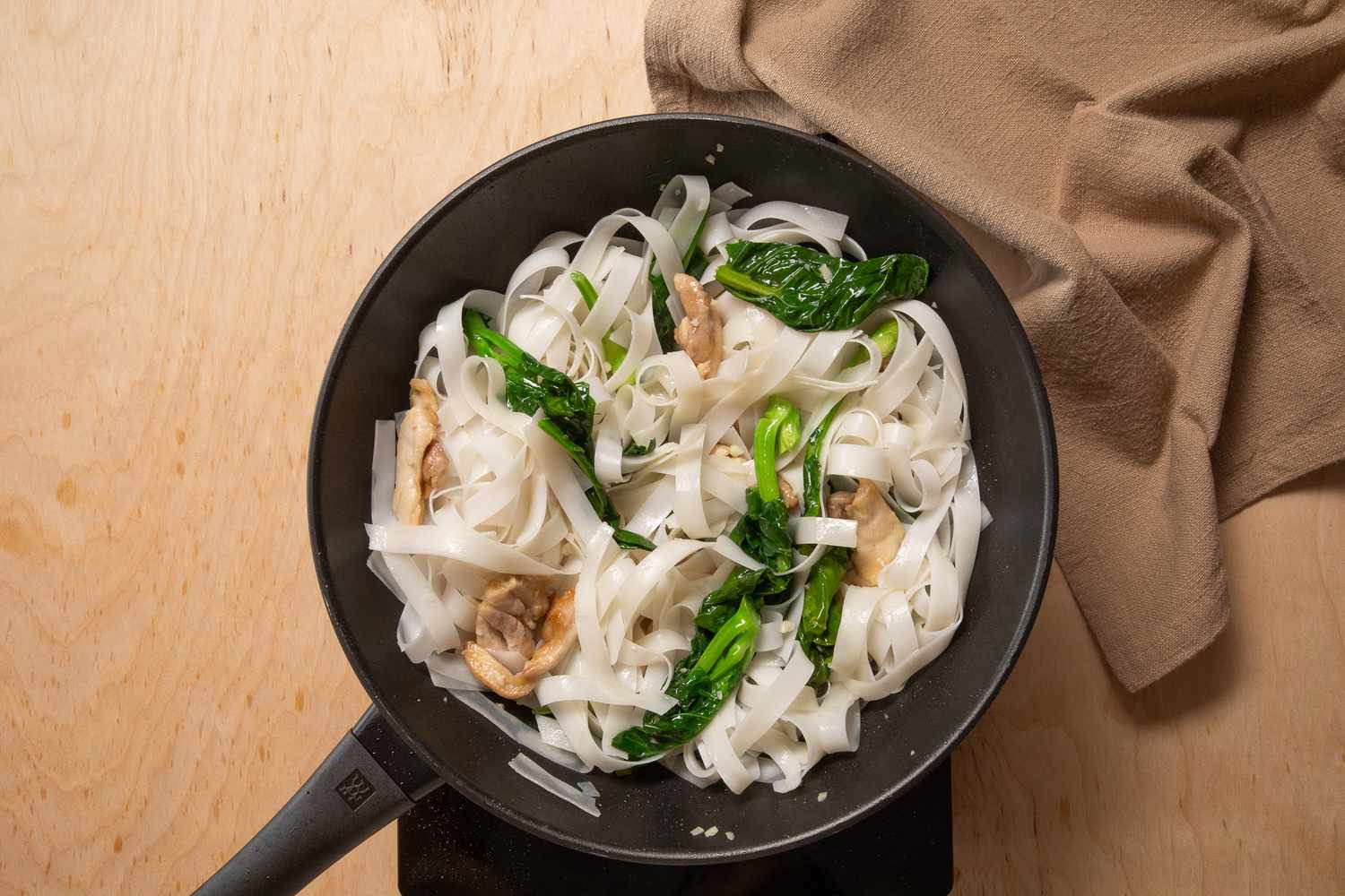 Chinese broccoli and rice noodles added to the wok for pad see ew recipe