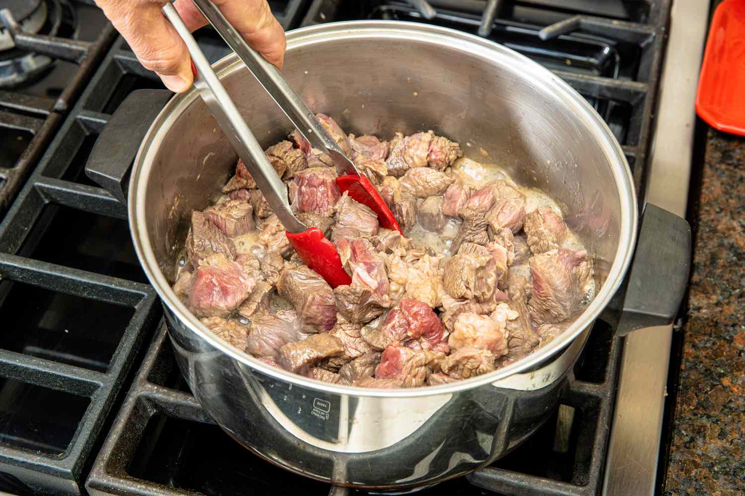 Beef Chuck Cooked in a Pot on a Stove and Stirred Using a Pair of Tongs for Beef Stew Recipe