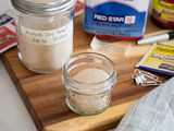 A wooden cutting board with a variety of yeast in their packaging and in mason jars to show how to store yeast.